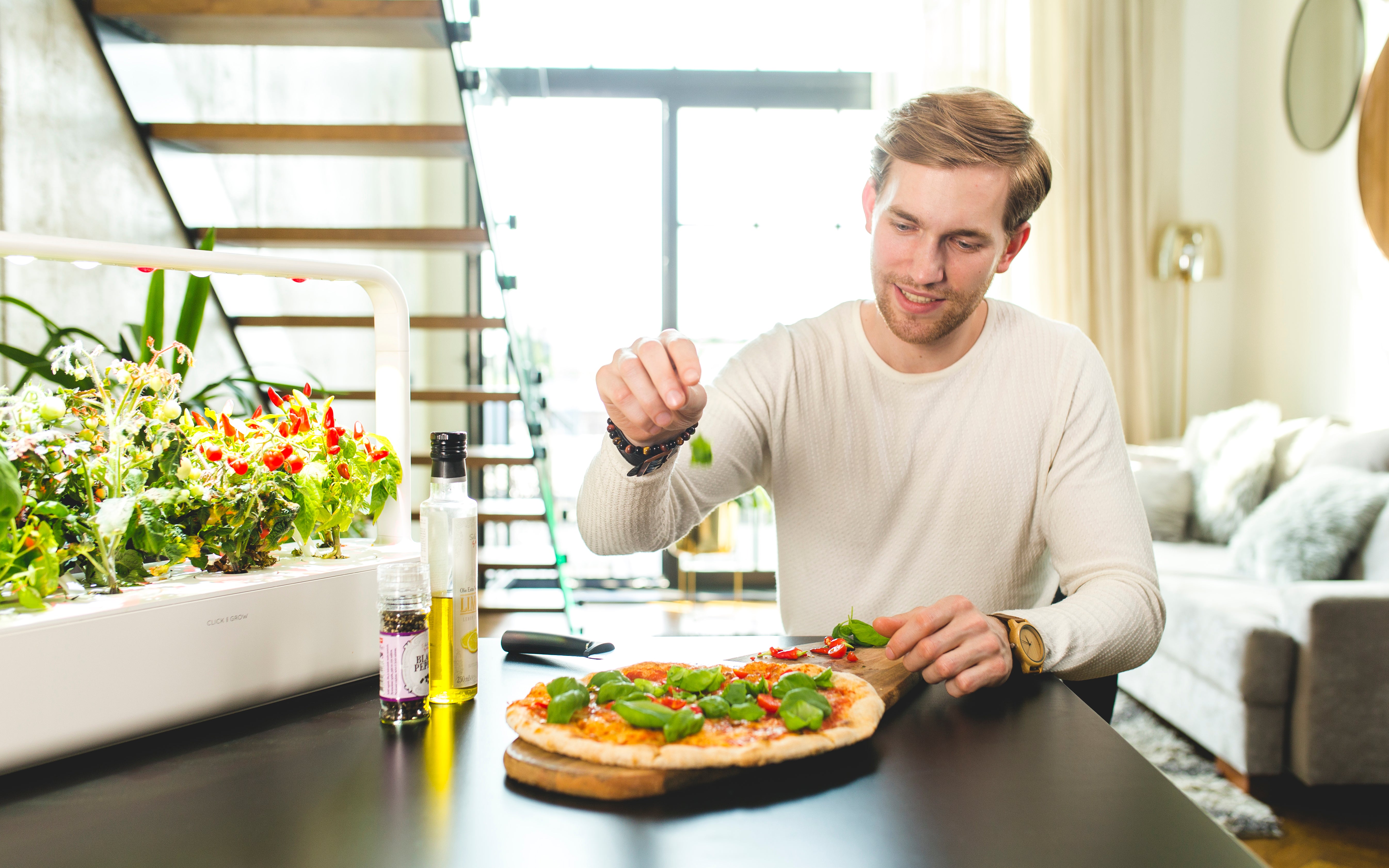 Click & Grow Smart Garden 9 with Man using fresh basil on pizza